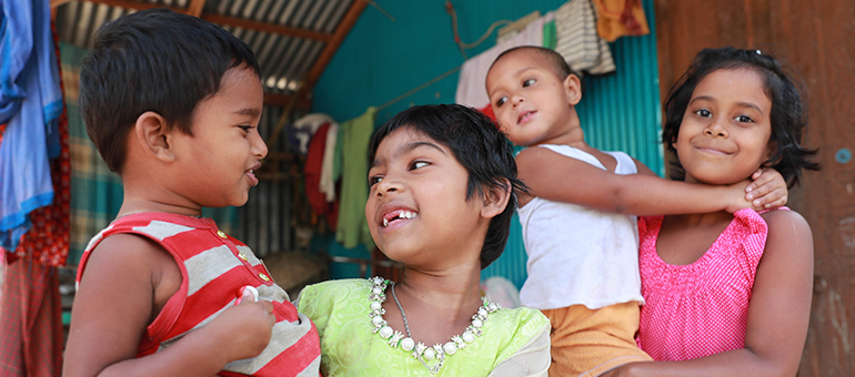 Two girls carrying their younger brother