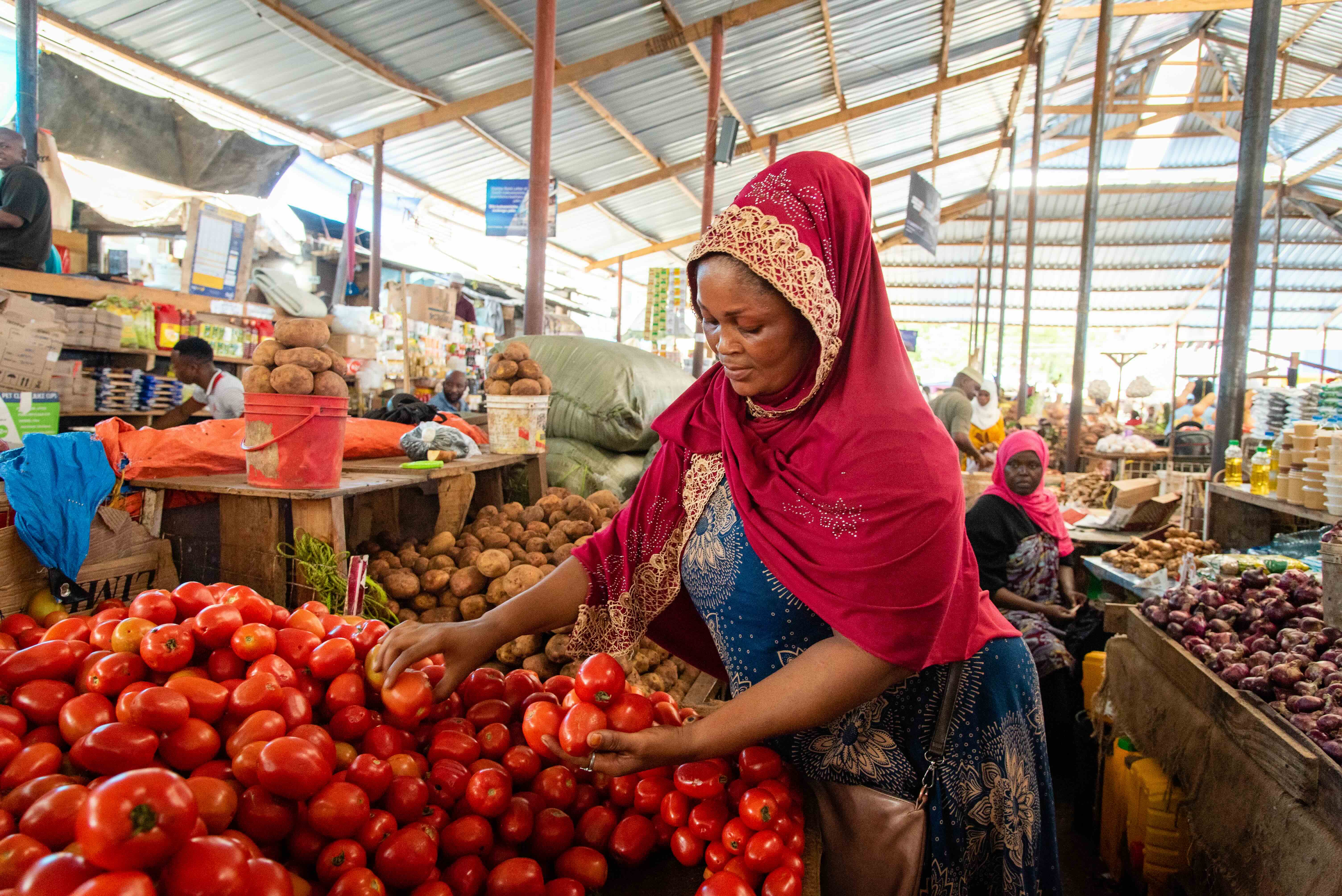 A woman picking tomatoes at a market stall