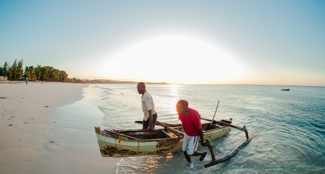 two people are pulling out a small boat out of the ocean