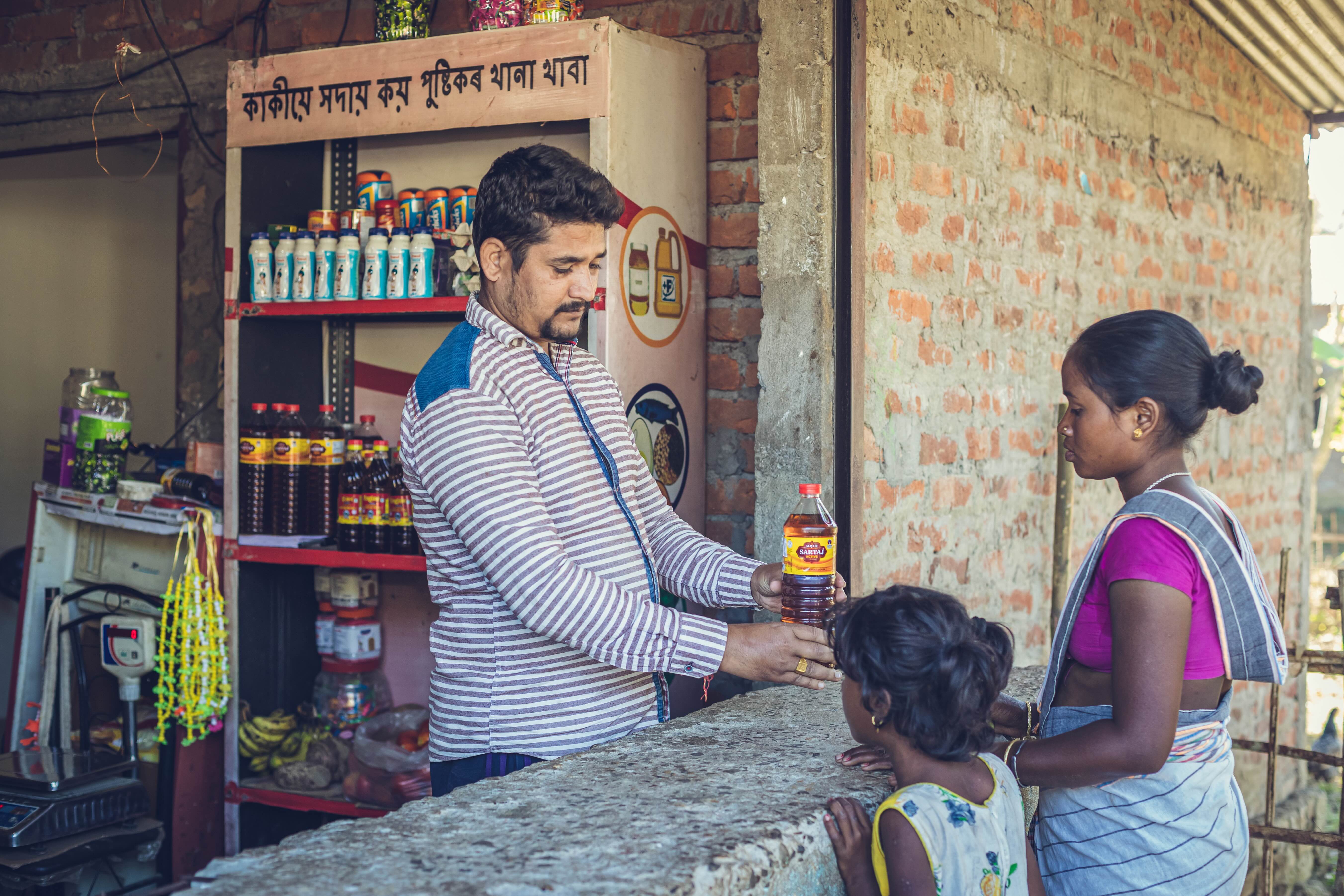 A male worker selling oil to two female customers