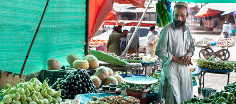 A man selling vegetables in Pakistan with a green background