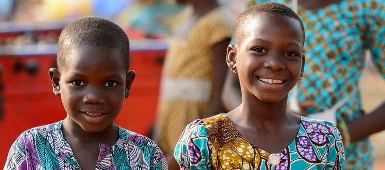 Two children in colorful clothes smiling to the camera