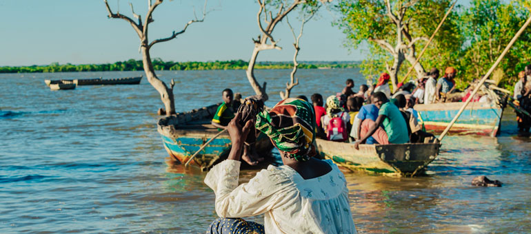 Woman giving her back to the camera and watching a group of boys going boating