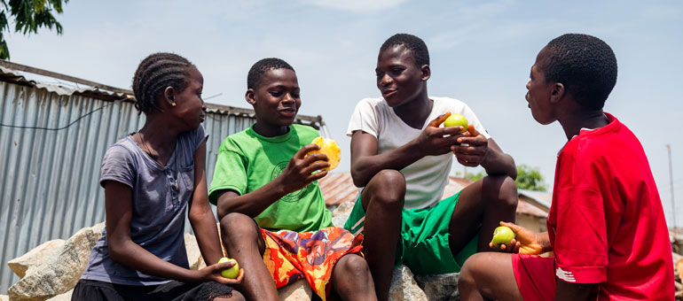 Four kids sitting down and eating and laughing together