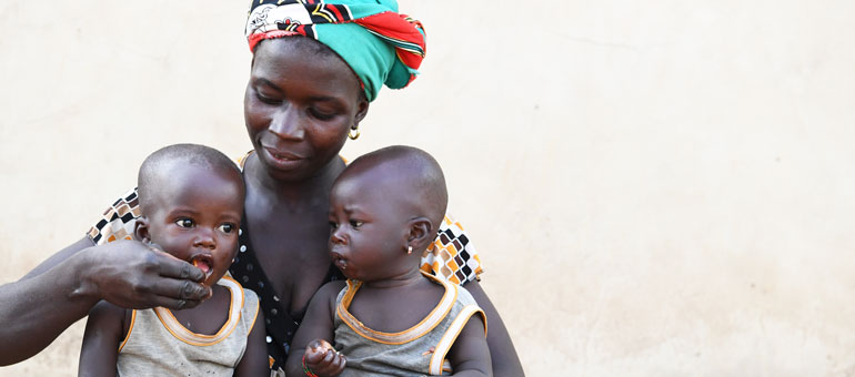 Woman gives food to her twins in Cote d'Ivoire