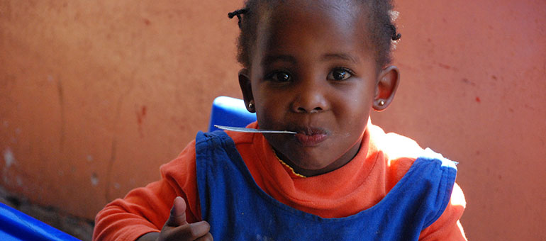 Little African girl with a spoon in her mouth 