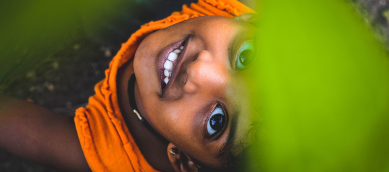 Little Indian girl smiling towards the camera in orange clothes