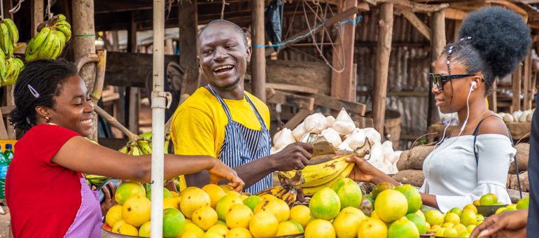 Woman buying bananas from couple in Africa market