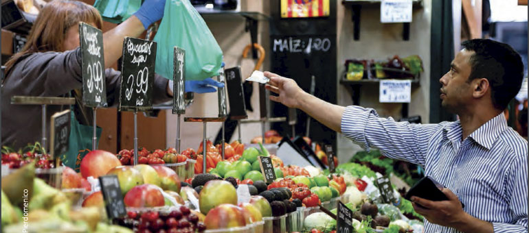 man paying at the market while woman hands bag