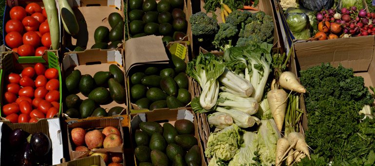 Market stall with avocado, tomatoes, aubergines and apples