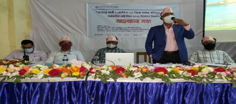 Men sitting behind a table while one of them speaks with a microphone