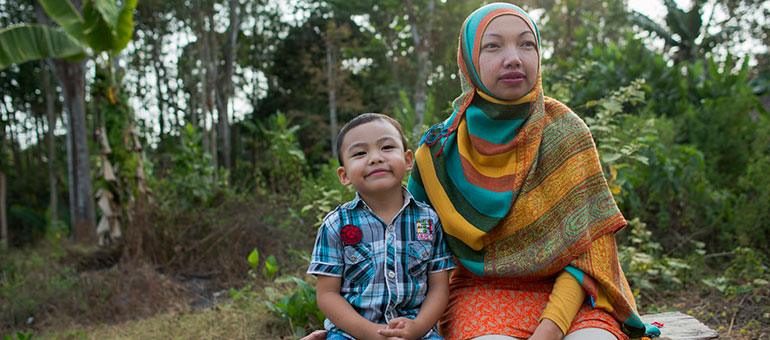 Mother and son sitting on a bench smiling in Indonesia