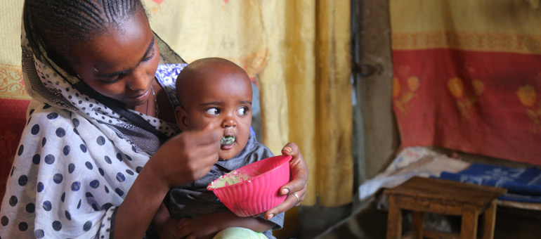 Mother feeding porridge to her baby in Ethiopia
