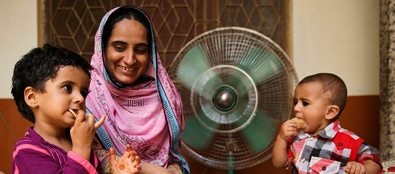 Mother with little girl and son eating bread in Pakistan