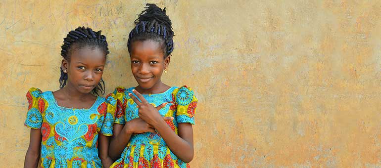 Two Nigerian girls against beige wall