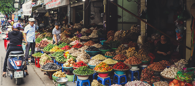 Person in scooter in front of vegetable stand