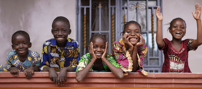 Five African Children Greeting Bypassers From A Colonial House Balcony