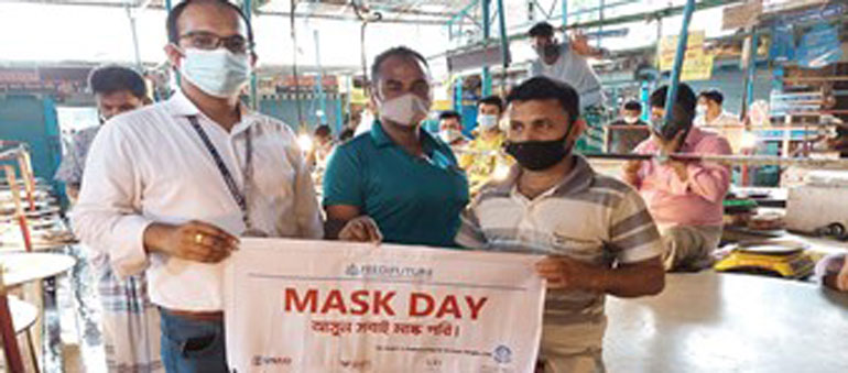 Three men in Dhaka holding a banner and wearing masks