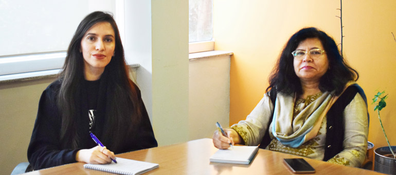 Two women sitting down on a table in Pakistan writing down