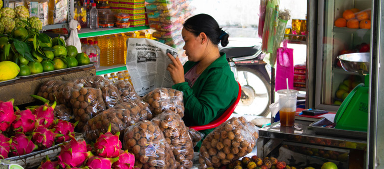 Woman reading newspaper next to food