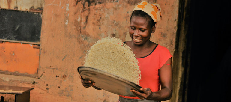 woman smiling and shaking rice basket Nigeria