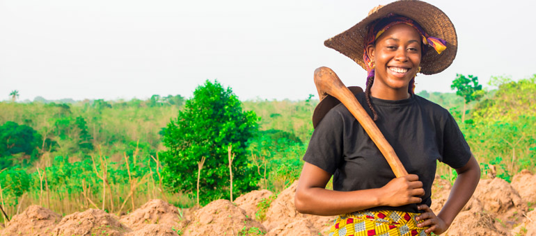 Smiling woman in the field wearing a hat and black shirt