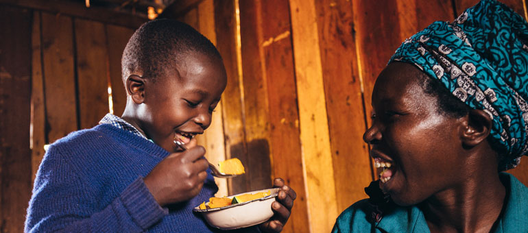 Woman smiling with kid while he is eating