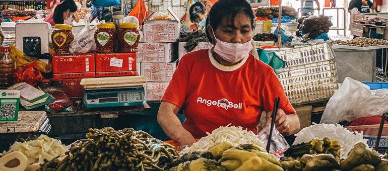 Woman wearing mask while sorting food in a market