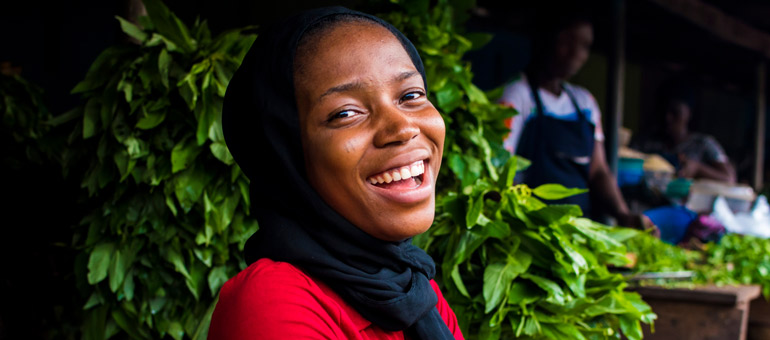 Young African woman smiling with green leaves in the background