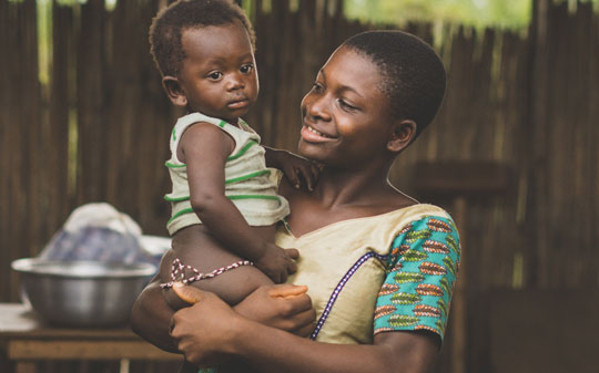 Woman holding a baby in Rwanda and smiling