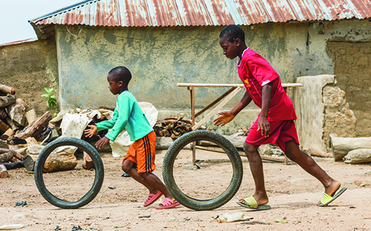 two children playing with spinning wheels against a neighbourhood backdrop
