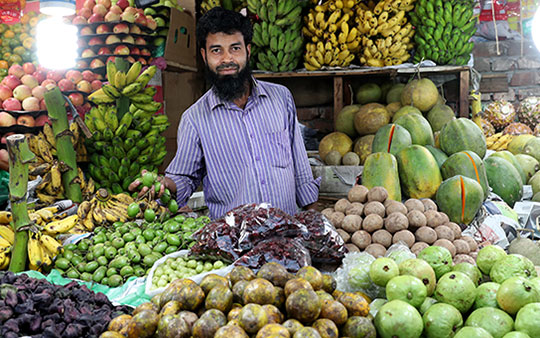 Man selling fruits and vegetables in an indoor market in Bangladesh