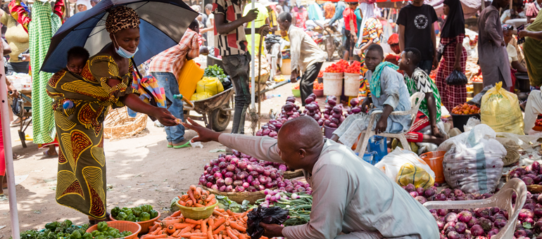 A male vendor taking money from a lady after purchase.