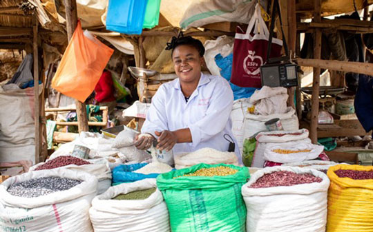 Woman holding beans out of a plastic bag from the market