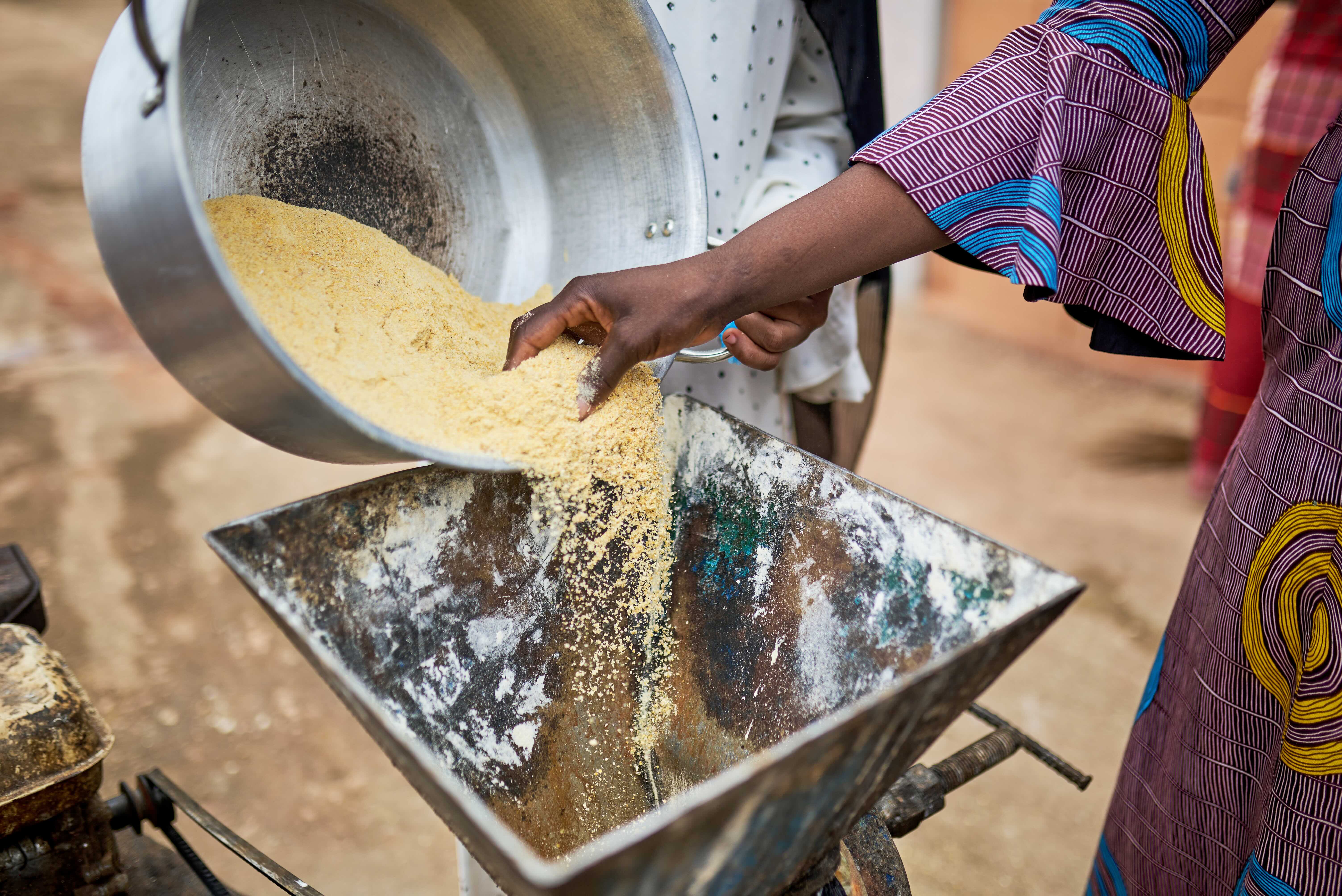 Woman putting maize flour into a processor