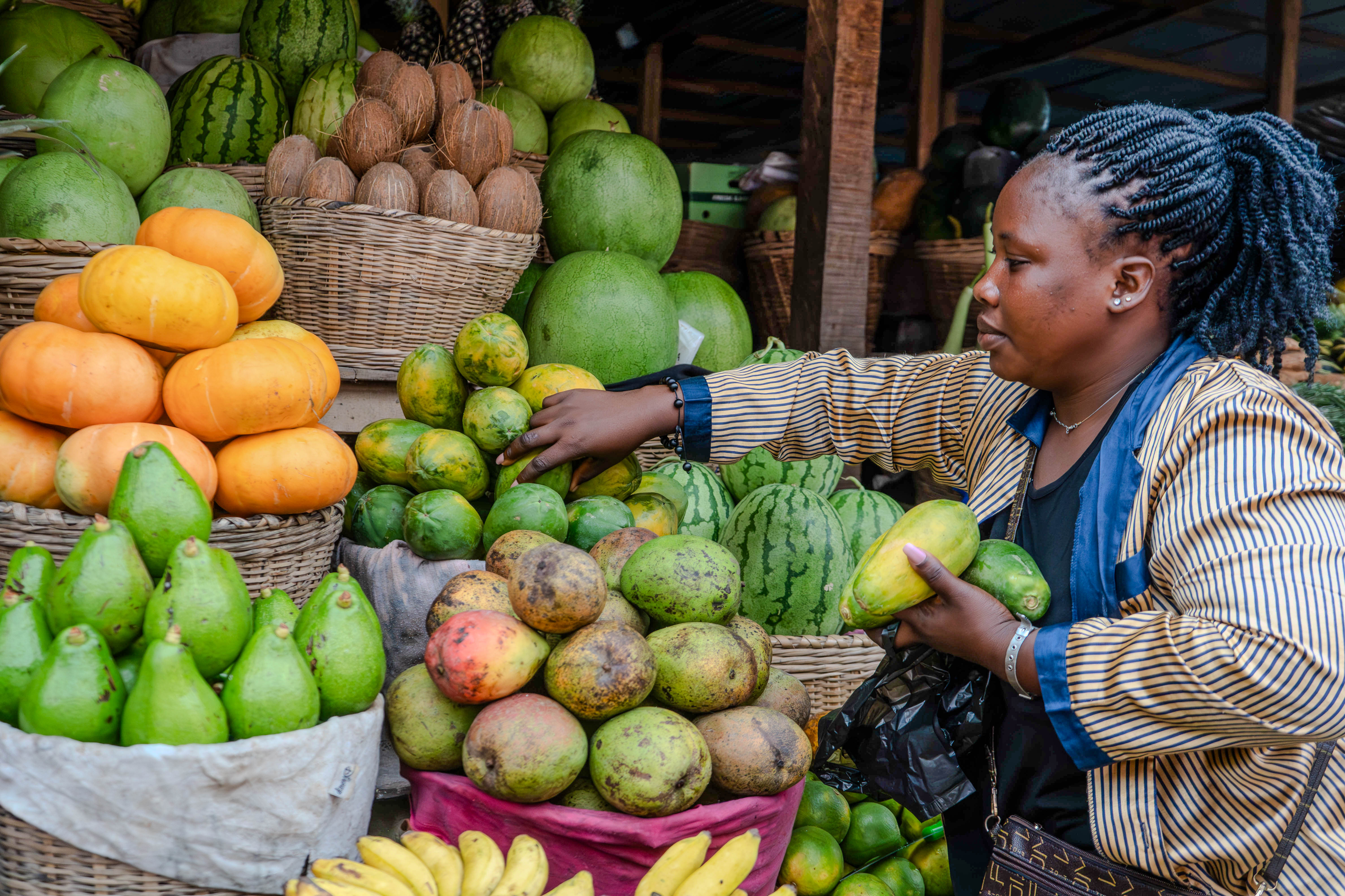 A woman displaying fruits and vegetables at a market