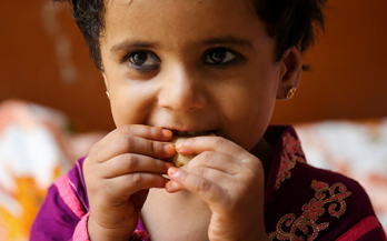 Little girl on pink shirt eating fortified bread in Pakistan