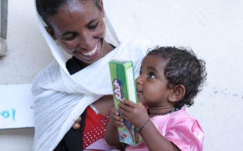 Mother holds her baby on her lap and smiles at her, Ethiopia