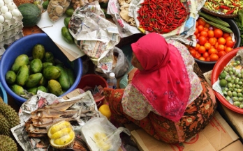 Woman sitting in the middle of vegetables, fish and fruits