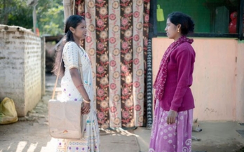 Lakhinayak (L) talking to a woman about the importance of balanced diet