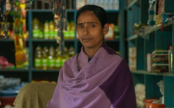 Woman in India stands in front of her shop