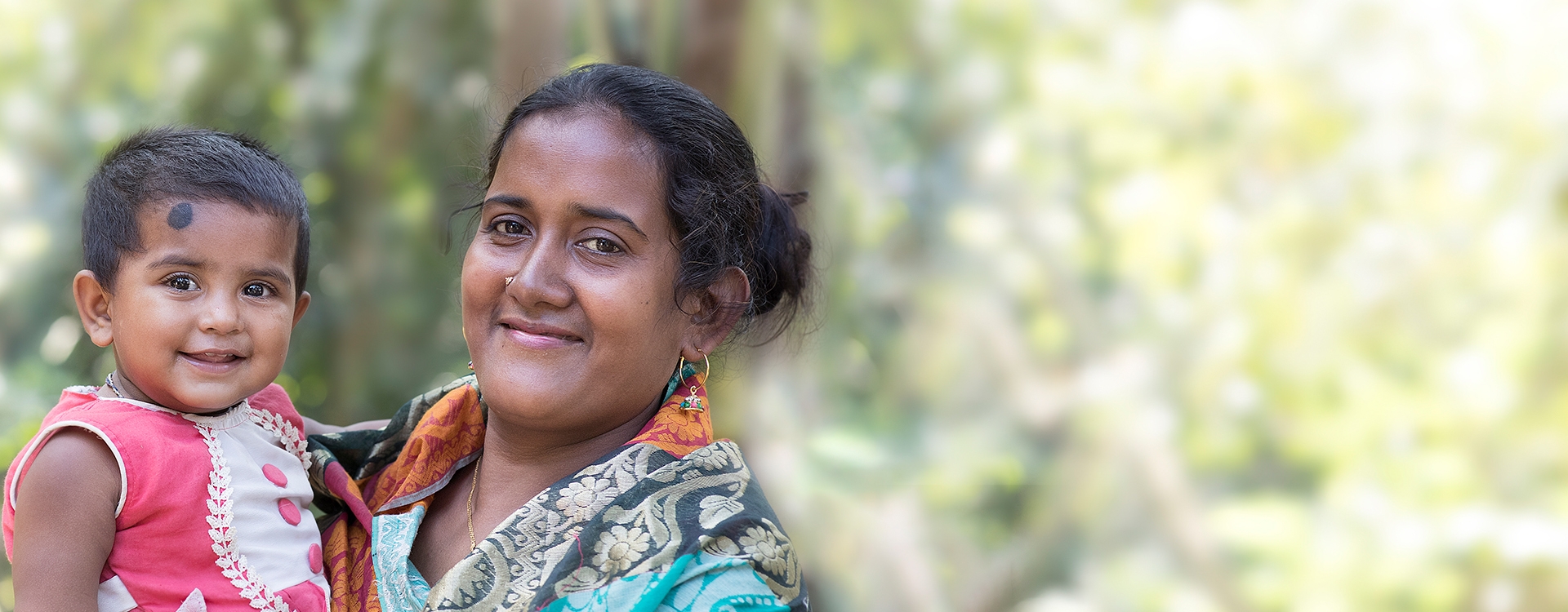 A woman smiling and carrying a small child