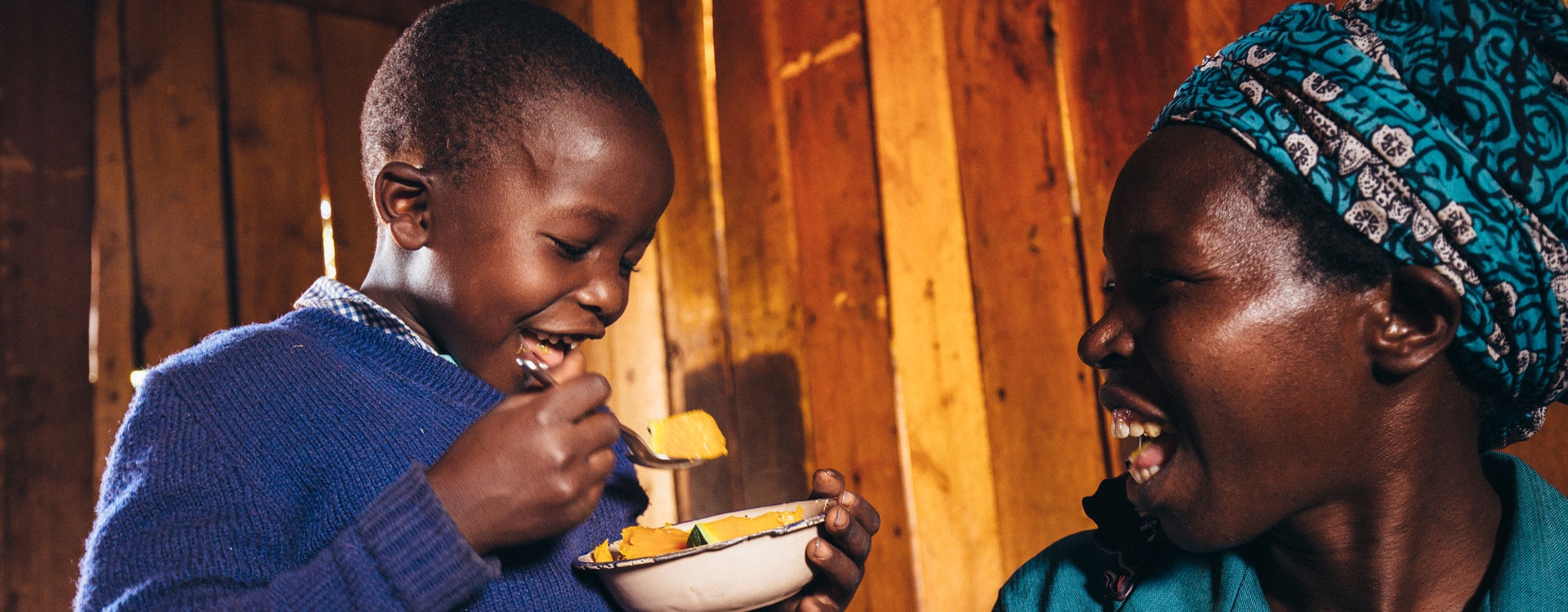 Woman smiling at kid while he is eating