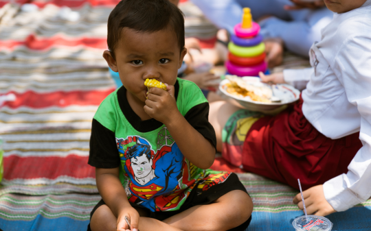 A young boy eating corn