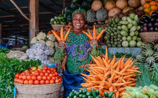 happy seller displaying her fruits and vegetables at the market