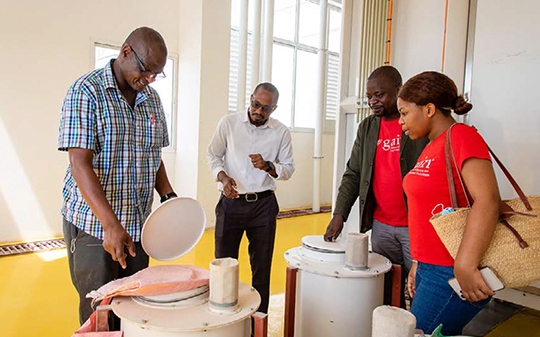 two GAIN workers look on at a man using a machine