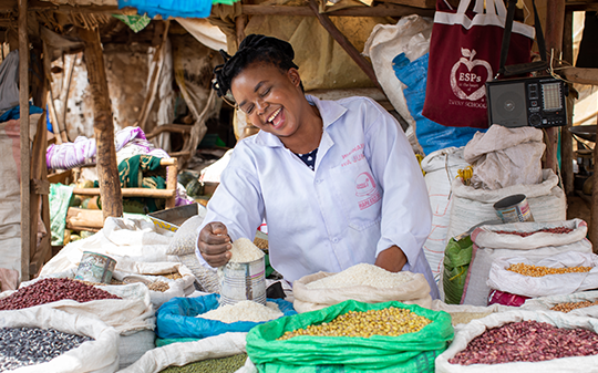 a woman smiling with crops in bags