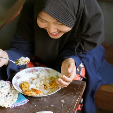 A lady eating rice, vegetables and chicken in Indonesia