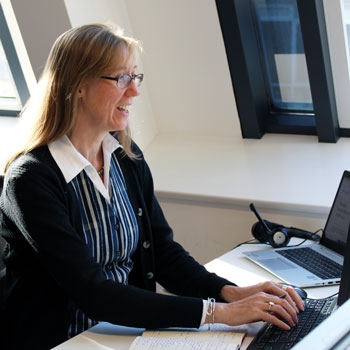 Catherine Gee sitting at her laptop and smiling while typing