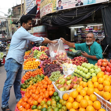 Man buying fruits from a market seller in Bangladesh